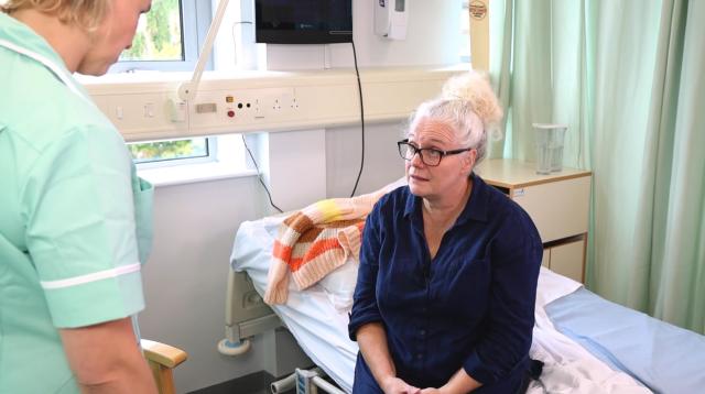 Nurse speaking to a patient on a ward